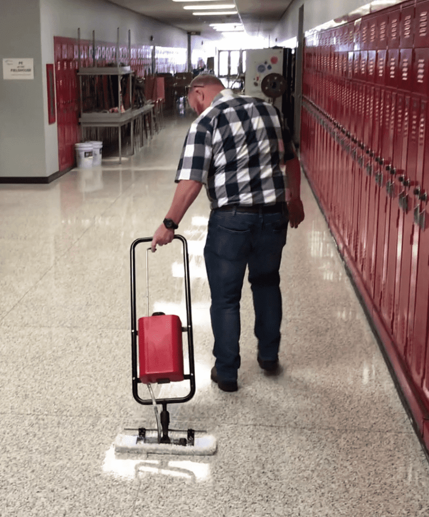 A worker coats a hallway floor with a Micro-Trak Plus