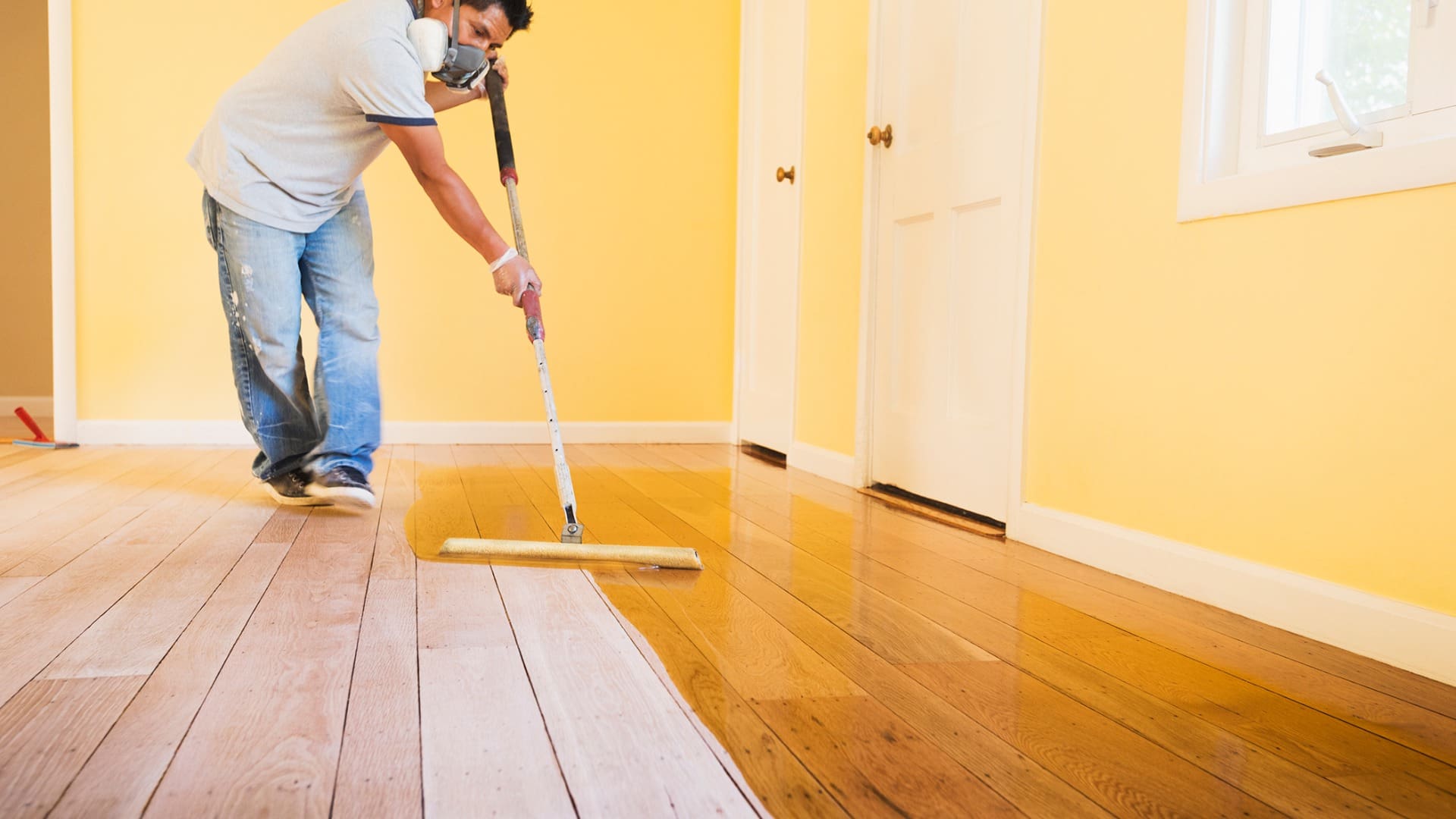 a person applying wax on hardwood floor with mop