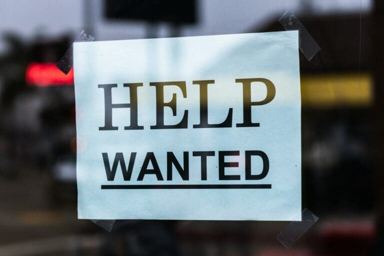 A help wanted sign is posted in a window