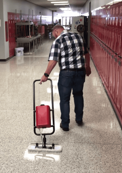 A worker coats a hallway floor with a Micro-Trak Plus
