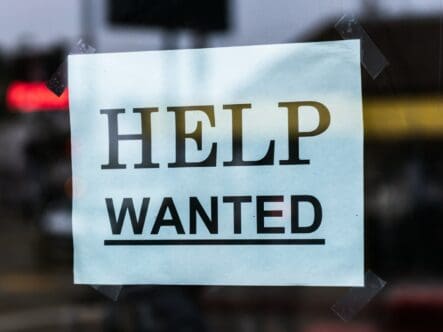 A help wanted sign is posted in a window