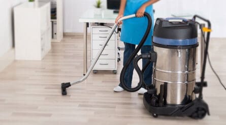 a person cleaning floor with a commercial vacuum cleaner.