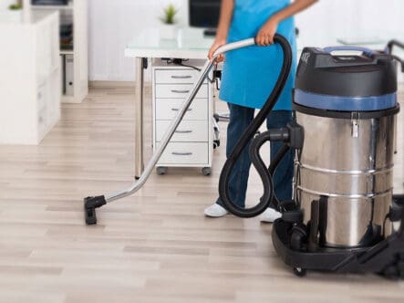 a person cleaning floor with a commercial vacuum cleaner.