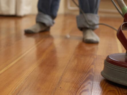Polishing hardwood floor with scrubbing machine.