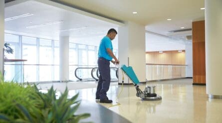 a person polishing tiles with a polishing machine in a commerical space.