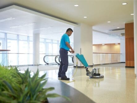 a person polishing tiles with a polishing machine in a commerical space.