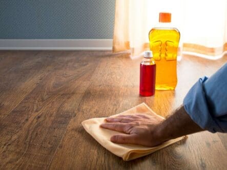 close shot of a hand waxing hardwood floor with cloth.